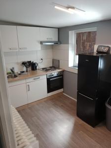 a kitchen with white cabinets and a black refrigerator at Stadtnest Katharine in Flensburg