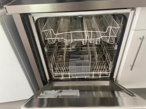an open dishwasher with a rack full of dishes at Apartment 65 m2 SE Rez de Jardin 2 chambres in Varetz