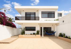 a white house with a balcony and flowers at Flip Flop House in Puerto Villamil