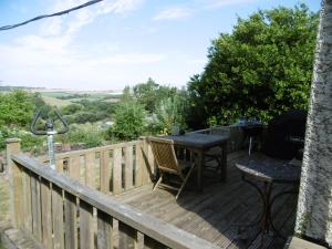 a wooden deck with a table and chairs on it at 2 Little Meadow Cottages in Dartmouth