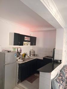 a kitchen with black cabinets and a white refrigerator at Aïn turk oran in Aïn El Turk