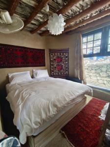 a bedroom with a bed with white sheets and a window at Cloud Nine And A Half in Hunza Valley +10 photos