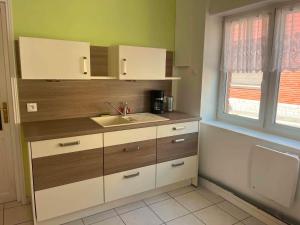 a kitchen with white cabinets and a sink and a window at Chez JC in Drouvin-les-Marais