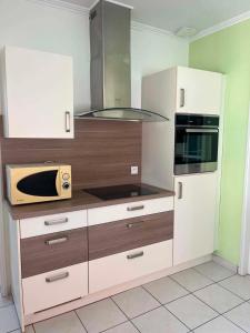 a kitchen with white cabinets and a microwave at Chez JC in Drouvin-les-Marais
