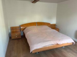 a bedroom with a bed with a wooden headboard and a night stand at Chez JC in Drouvin-les-Marais