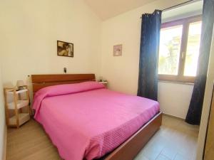 a bedroom with a pink bed and a window at Maison di Mario in Tresnuraghes