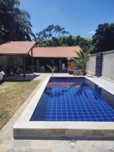 a swimming pool with blue tiles on the side of a house at Sitio ALI in Cachoeira Paulista