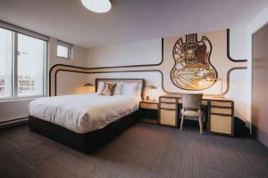 a hotel room with a bed and a guitar on the wall at Hotel Burnaby in Burnaby