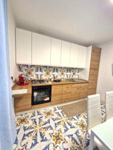 a kitchen with white cabinets and blue and white tiles at Sea View MdG in Marina di Gioiosa Ionica