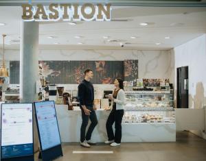 a man and woman standing in front of a bakery at Hotel Burnaby in Burnaby