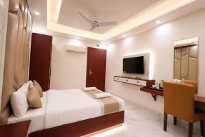a bedroom with a bed and a desk and a television at The Vatika Paradise in Ayodhya