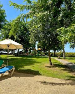 a park with a chair and an umbrella and a playground at Balansea Resort in Caesarea