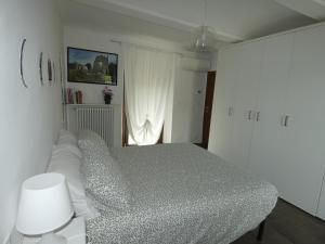 a white bedroom with a bed and a window at Ca' Fontanetta Holiday Home in Caprie