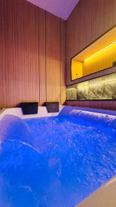 a large tub filled with blue water in a room at جناح فاخر بإطلالة على البحيرة وجاكوزي خاص in Al Khobar