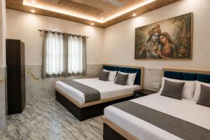 a room with two beds and a painting on the wall at Hotel PKD Vrindavan Near 100 Futta Main Road in Vrindāvan +5 photos