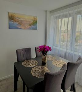 a dining room table with chairs and a vase of flowers at Silver II in Świnoujście +12 photos