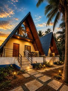 a house with a pyramid roof with stairs and a palm tree at Aastha Gokarna in Gokarn
