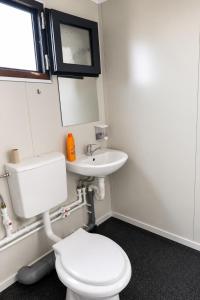 a bathroom with a white toilet and a sink at NIBIRU OFFICIAL ACCOMMODATION LUNR Camp in Costinesti