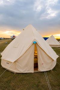 a large tent in a field with the sunset in the background at NIBIRU OFFICIAL ACCOMMODATION LUNR Camp in Costinesti