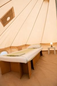 a small bed in a tent with a table at NIBIRU OFFICIAL ACCOMMODATION LUNR Camp in Costinesti
