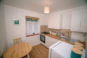 a kitchen with white cabinets and a wooden table at Avalonia in Glastonbury