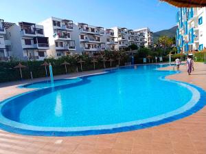a large blue swimming pool with buildings in the background at Alta-Home cabo in Cabo Negro