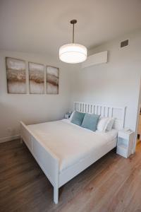 a white bed in a white bedroom with a light at Saratoga Beach Villa 6 in Oyster Bay