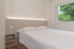 a white bedroom with a bed and a window at Altavista Aura in Molveno