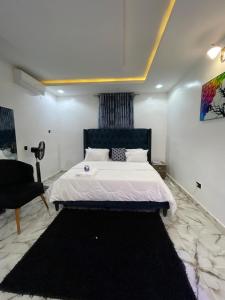 a bedroom with a large bed and a chair at At Kora Apartment and Shortlets in Asaba