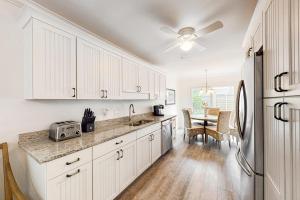 a kitchen with white cabinets and a refrigerator and a table at Twin Oaks 207 in Hilton Head Island