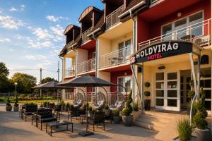 a hotel with chairs and umbrellas outside of it at Holdvirág Hotel in Sárvár