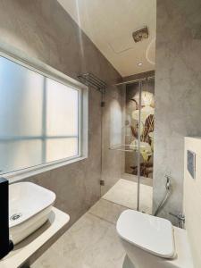 a bathroom with a toilet and a glass shower at Hotel Serenity Suites in Nagpur +27 photos