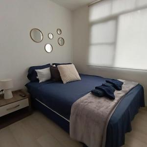 a bedroom with a bed with blue sheets and a window at Departamento en Manta amoblado con seguridad privada in Manta