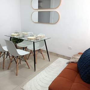 a dining room with a glass table and white chairs at Departamento en Manta amoblado con seguridad privada in Manta