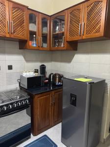 a kitchen with wooden cabinets and a stainless steel refrigerator at Aiden House Arusha in Arusha +19 photos