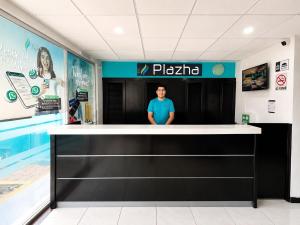 un uomo in piedi dietro il bancone di una farmacia di Hotel Plazha Express a Tuxtla Gutiérrez