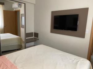 a bedroom with a bed and a flat screen tv on the wall at Flat com parque aquatico in Rio Quente +21 photos