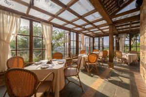 a dining room with tables and chairs and windows at Là Yên Retreat in Ấp Ða Lợi
