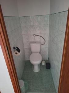 a bathroom with a toilet in a tiled room at Veszei Apartman in Békéscsaba +4 photos