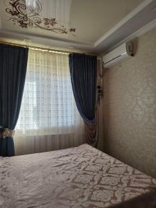 a bedroom with a bed and a window with blue curtains at Hamroz apartment in Navoi +2 photos