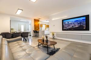 a living room with a couch and a tv on a wall at אחוזת שרון in Elifelet
