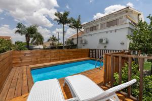 a backyard with a swimming pool and a wooden deck at אחוזת שרון in Elifelet