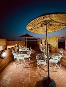 a patio with tables and chairs and an umbrella at Riad Kimee in Marrakesh