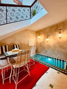 an infinity pool in a room with a table and chairs at Riad Kimee in Marrakesh