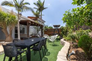 a patio with a black table and chairs and palm trees at אחוזת שרון in Elifelet