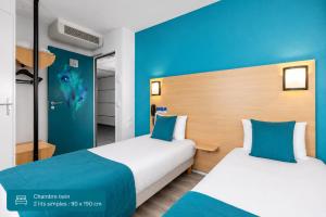 two beds in a room with blue walls at The Originals Access, Hôtel Innostar in Labège