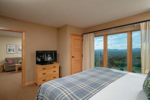 a bedroom with a bed and a tv and a window at Burke Mountain Hotel in East Burke