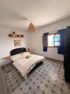 a bedroom with a bed in a room with blue curtains at Jara Cimrman surf house in Imsouane