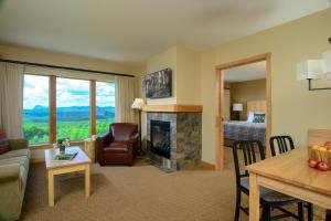 a living room with a fireplace and a bedroom at Burke Mountain Hotel in East Burke