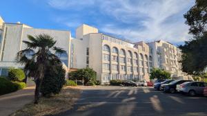a large building with cars parked in a parking lot at Résidence avec Piscine face au port 200m plage in La Rochelle
